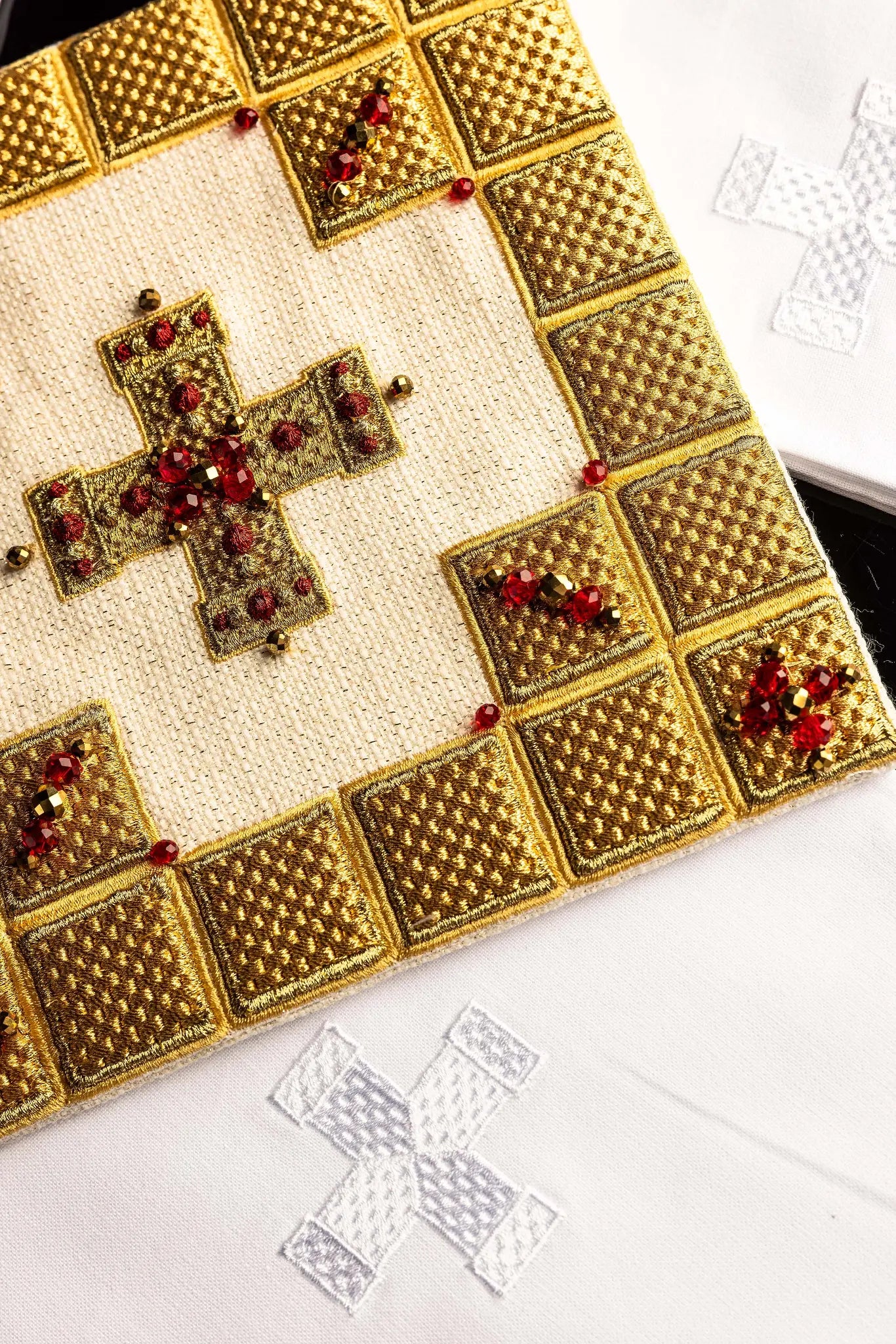 Ecru handmade chalice linen set with a pall featuring a dimensional gold cross, red hematite, and shimmering crystals, a corporal with a central cross, and a purificator and lavabo towel with embroidered crosses, all with scalloped edges.