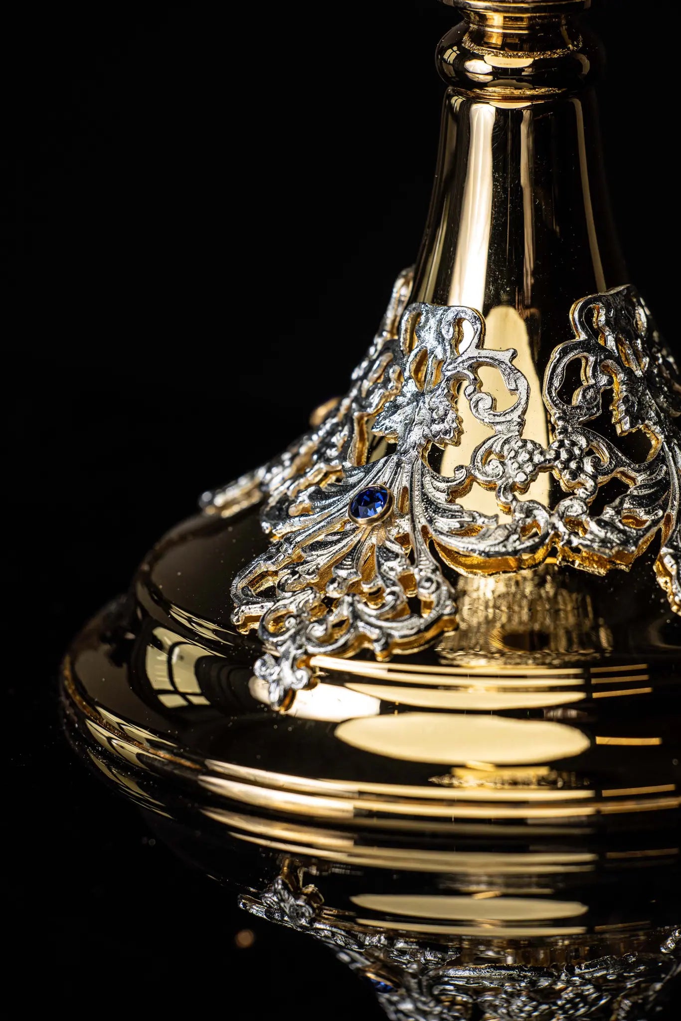 Handmade gold-plated liturgical chalice with silver-plated floral ornamentation and blue sapphire-like stones. The chalice features a decorated cup, nodus, and base.