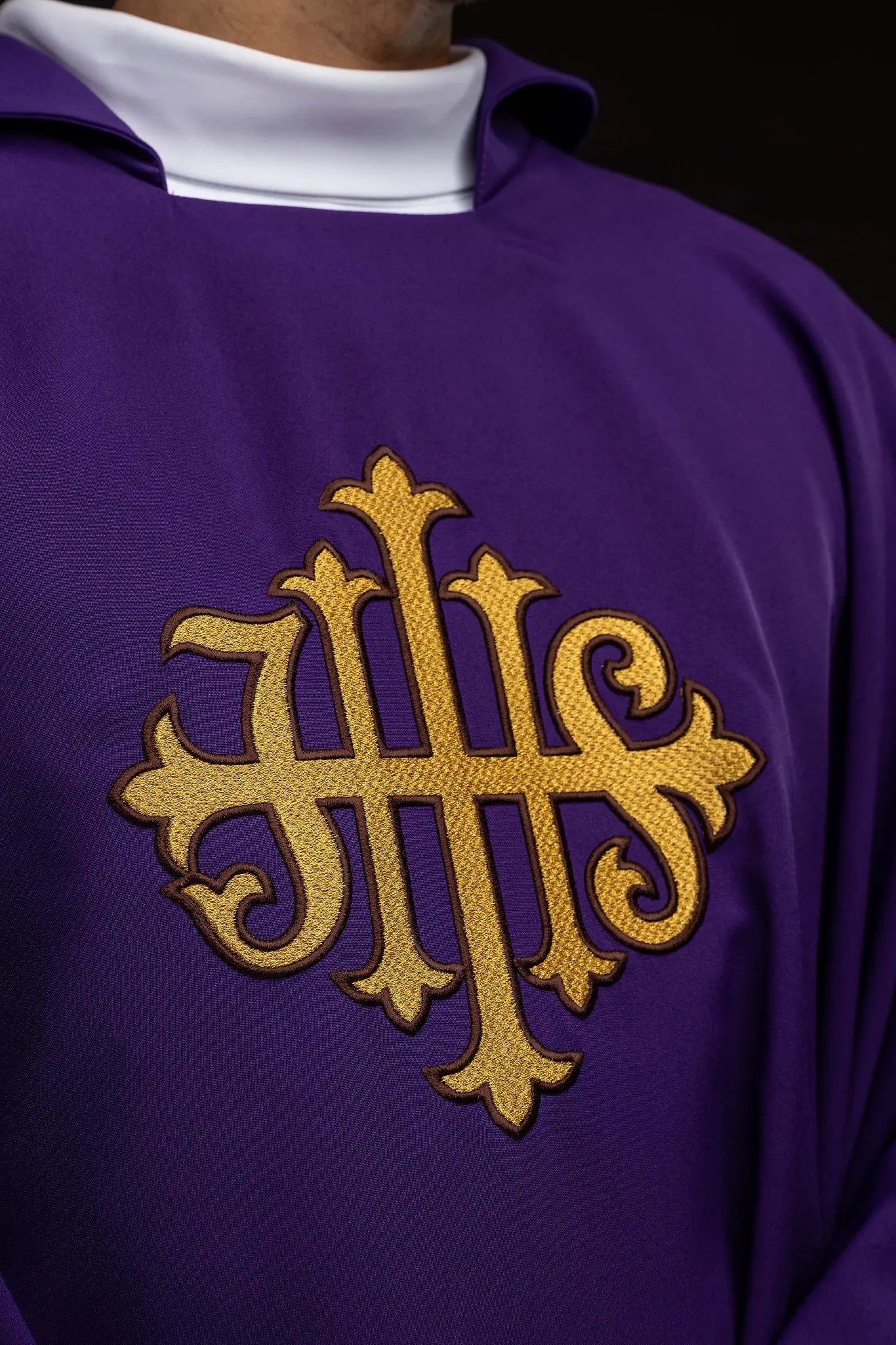 Purple chasuble with embroidered IHS symbol and gold trim, featuring a V-neckline and a matching stole.