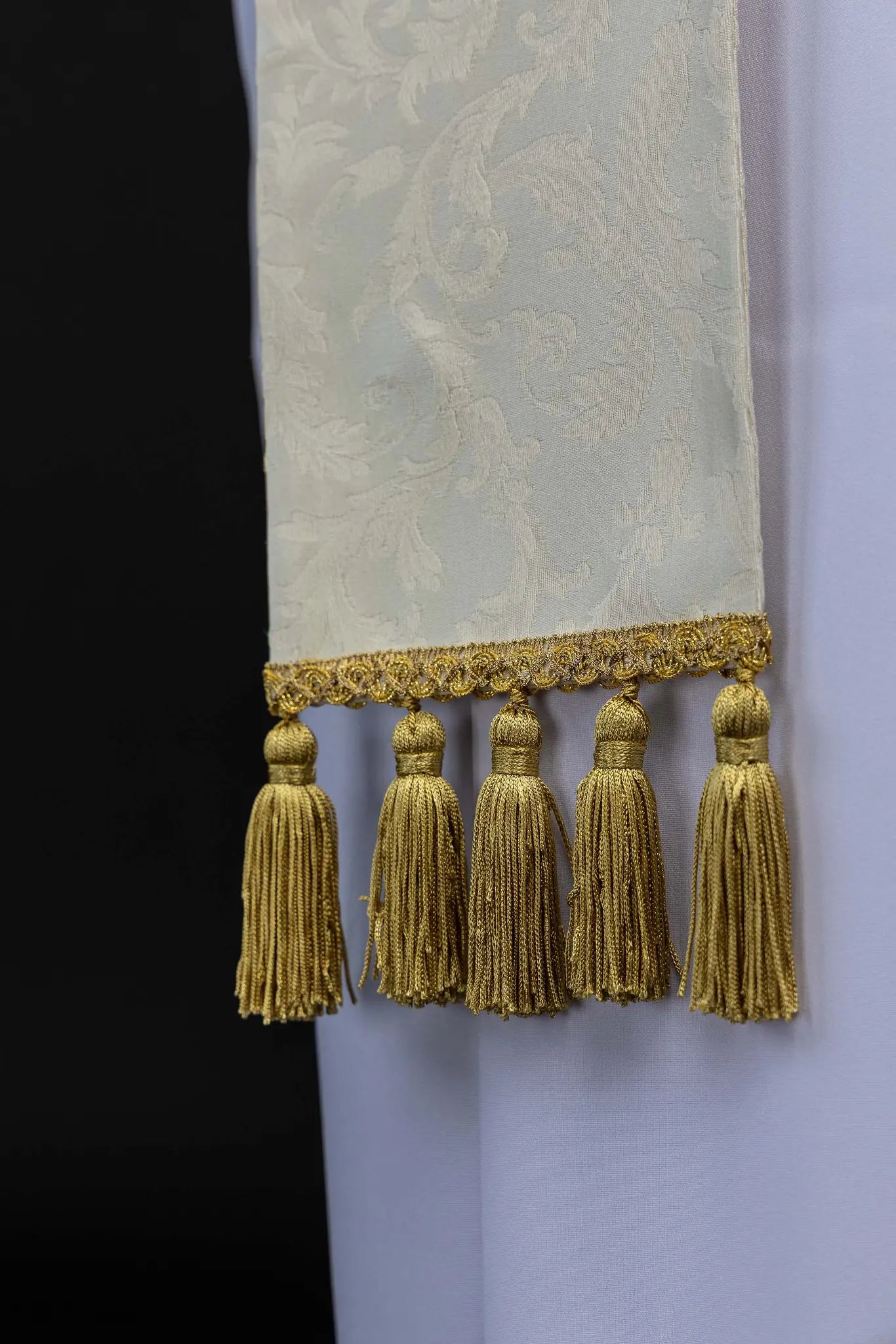 Ecru stole with Holy Family image on one side and IHS monogram on the other, featuring gold trim and tassels.
