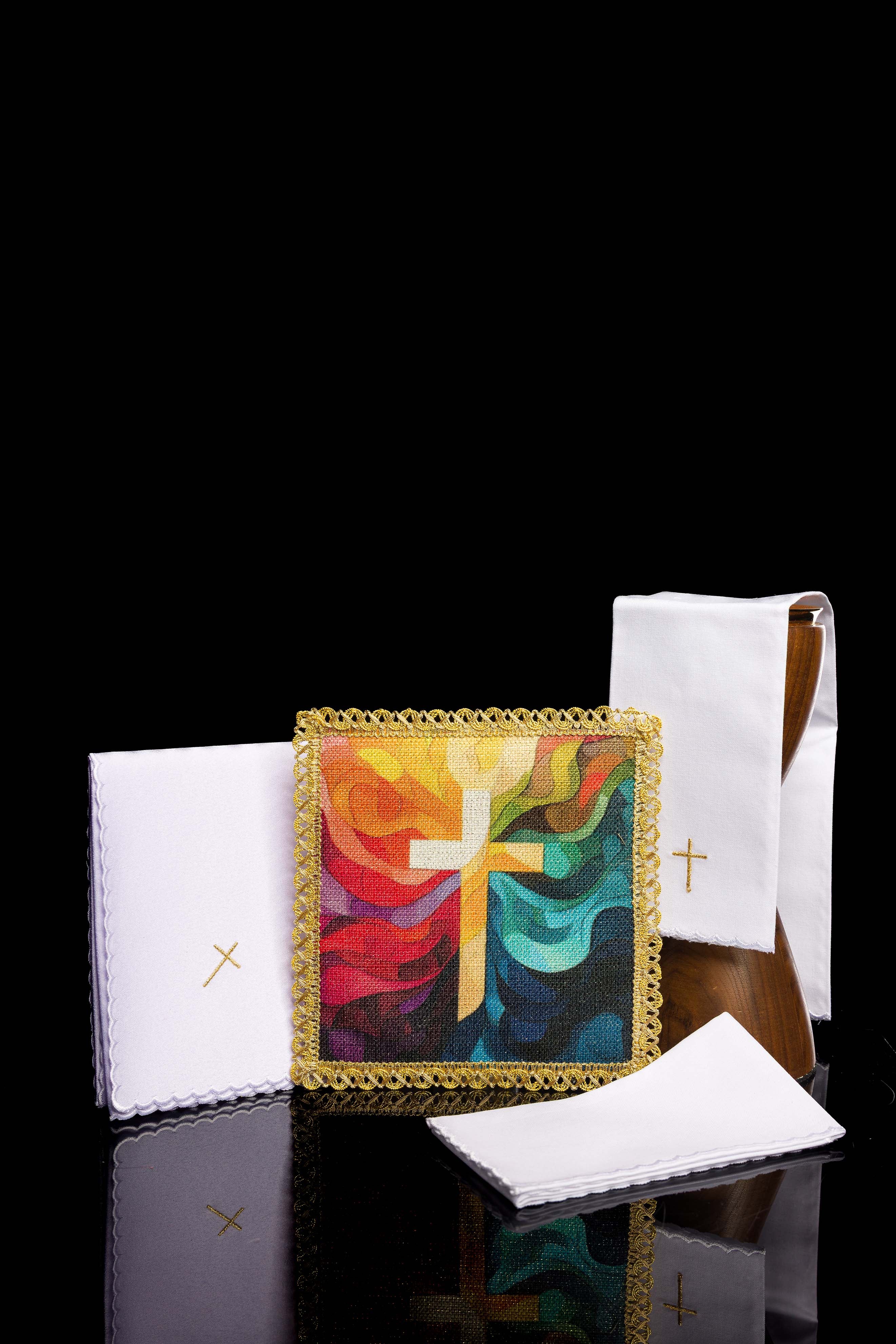 Pall with multicolour cross motif resting on folded white chalice linens with small gold embroidered cross