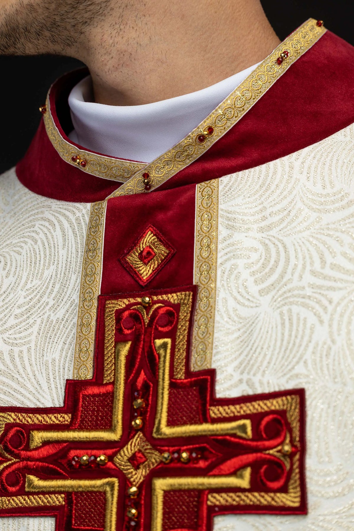 Kremowy ornat z haftowanym krzyżem i naturalnymi kamieniami, zbliżenie kołnierza i krzyża