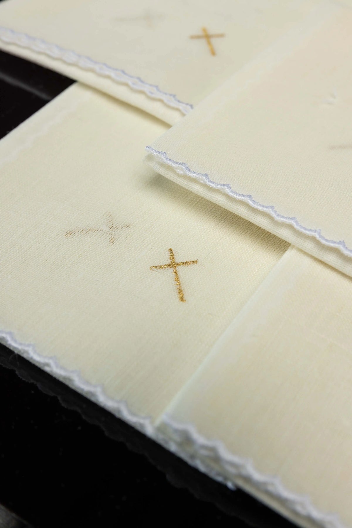 Ecru korporały liturgiczne z haftem złotego krzyża, widok detalu obszycia