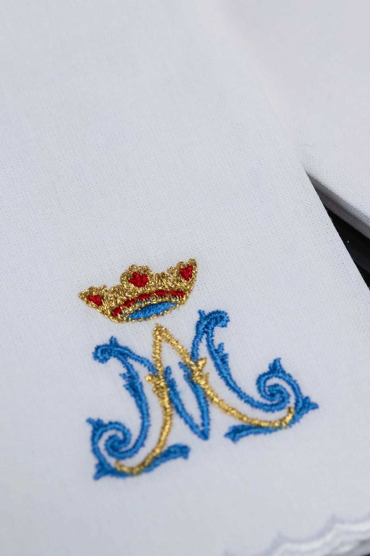 Biały puryfikaterz liturgiczny z haftem monogramu „M” i koroną, zbliżenie