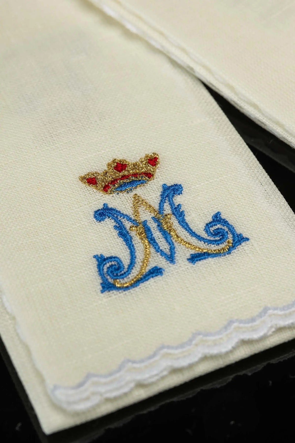 Ecru puryfikaterz liturgiczny z haftem monogramu i koronkowym wykończeniem, zbliżenie