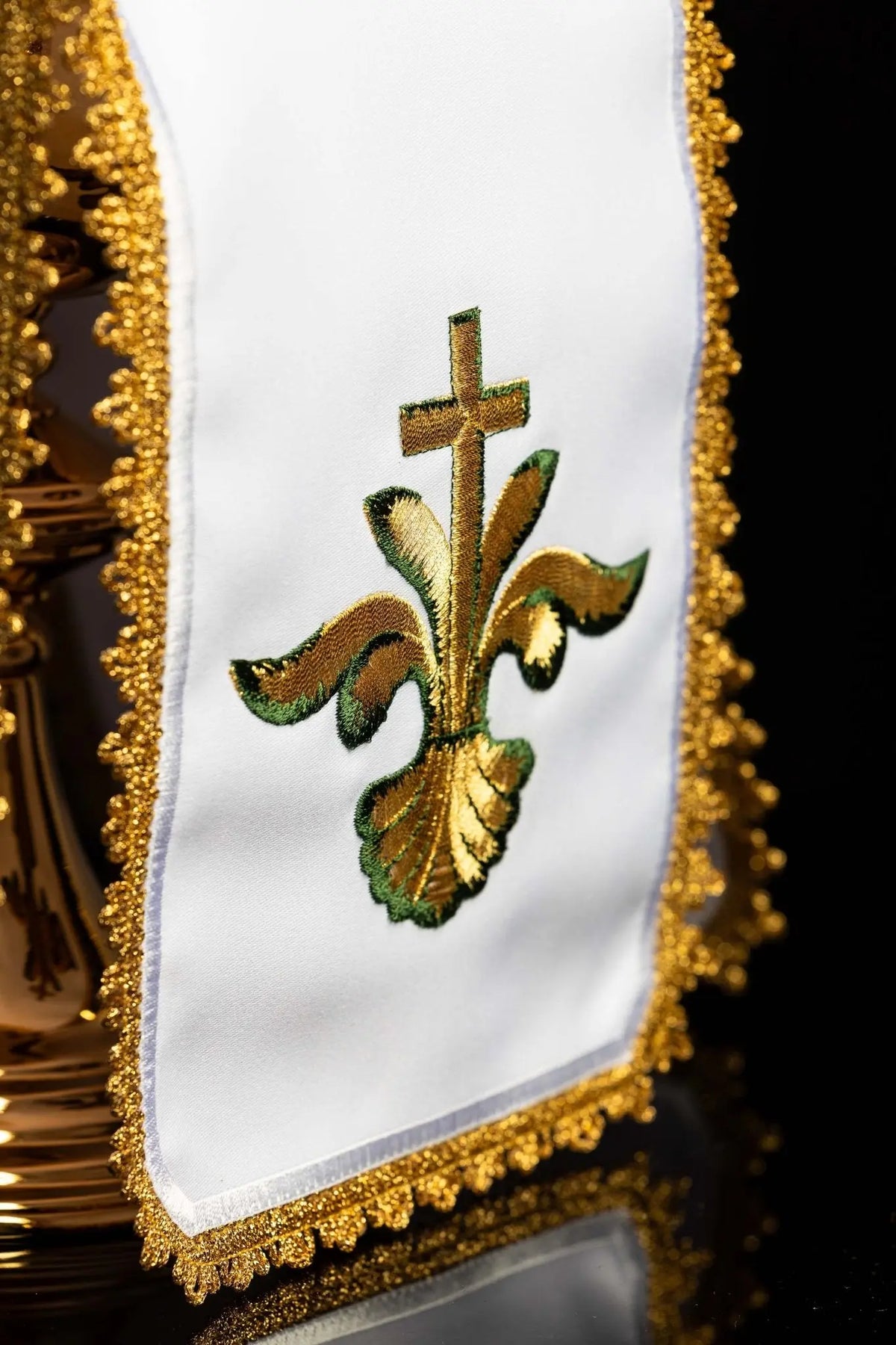 Biały welon na puszkę z haftowanym krzyżem i lilią, zbliżenie