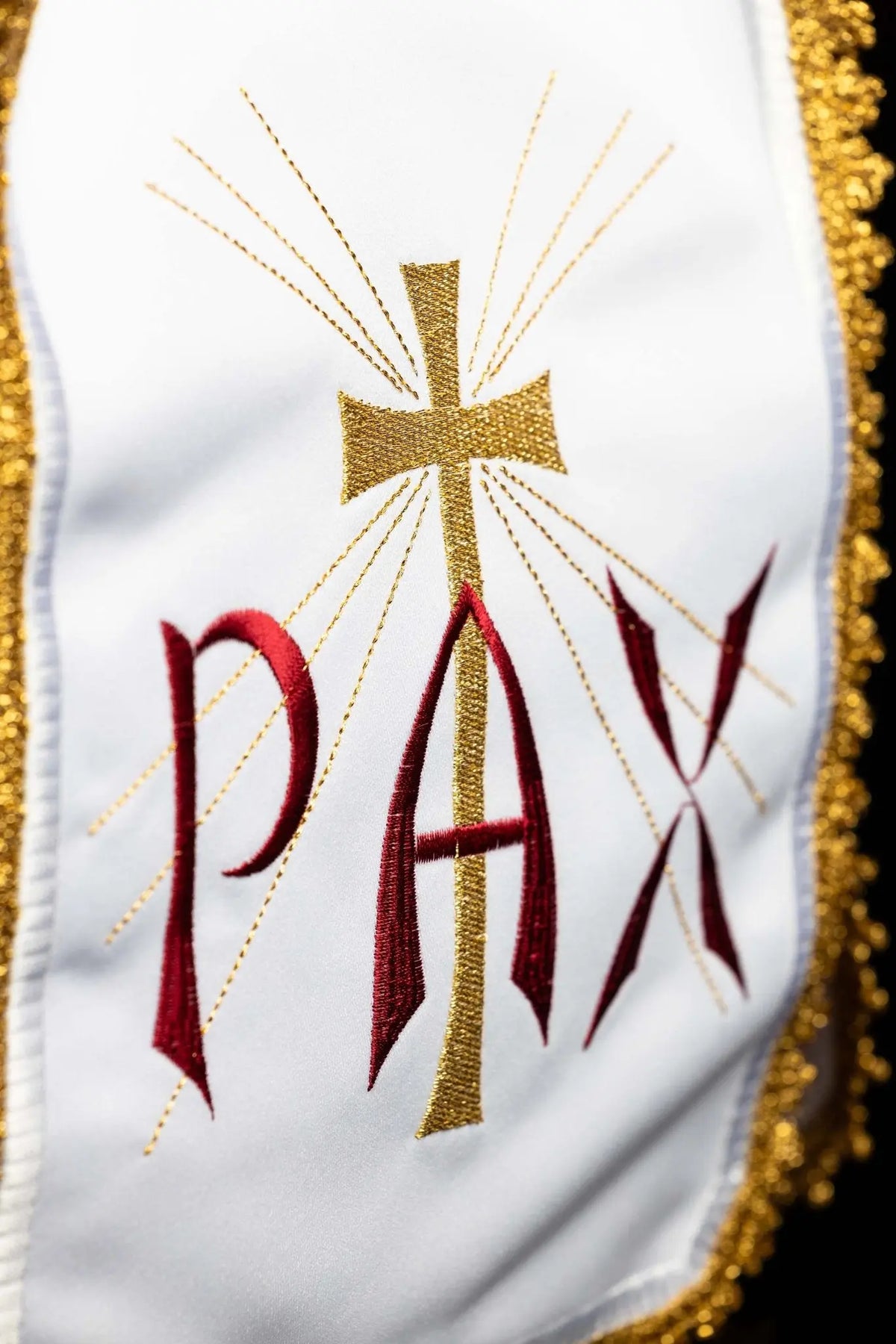 Biały welon na puszkę z haftem PAX i krzyżem promienistym, zbliżenie haftu
