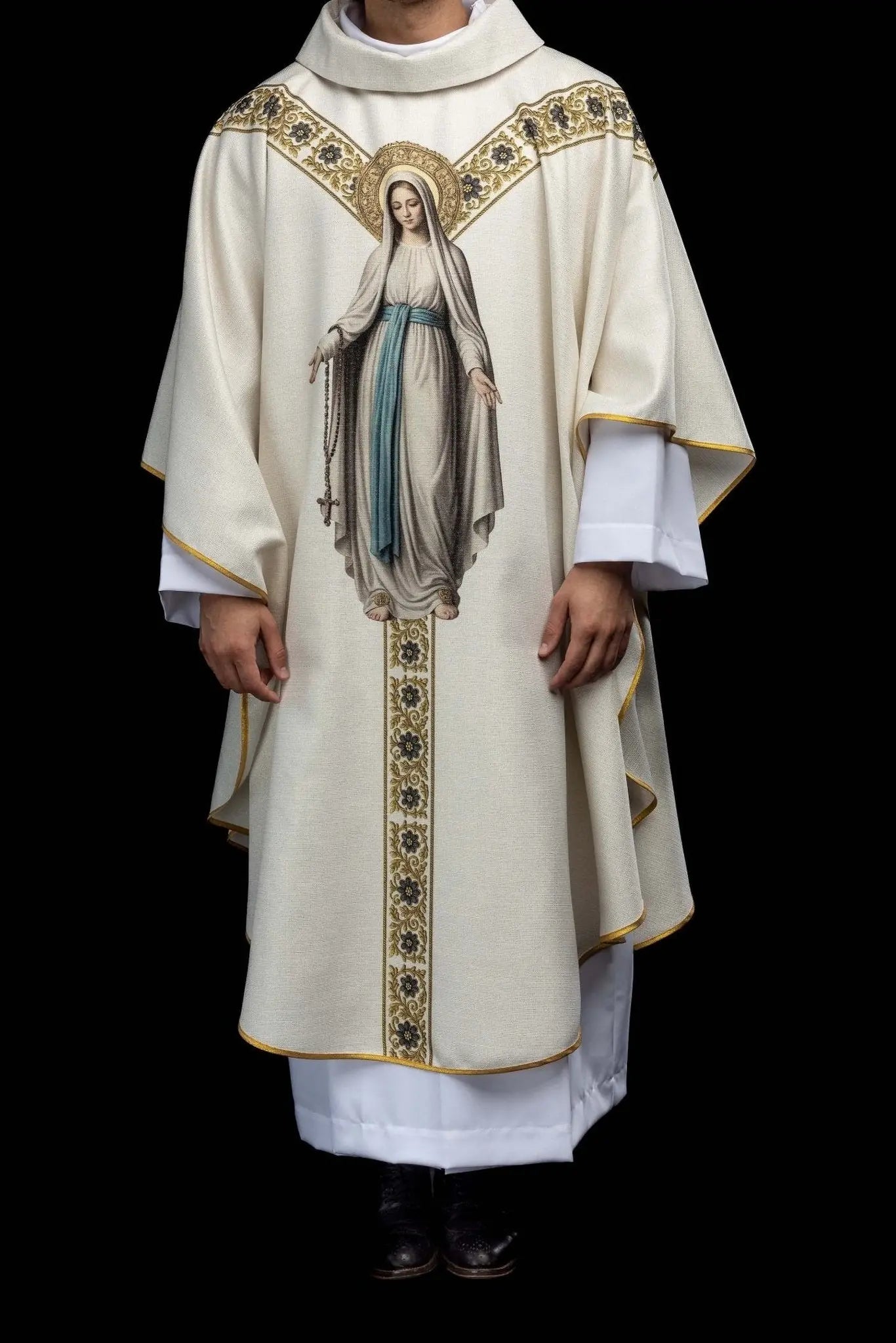 Ecru chasuble with printed image of Our Lady of Lourdes, featuring a blue sash and gold floral motifs, with a matching stole.