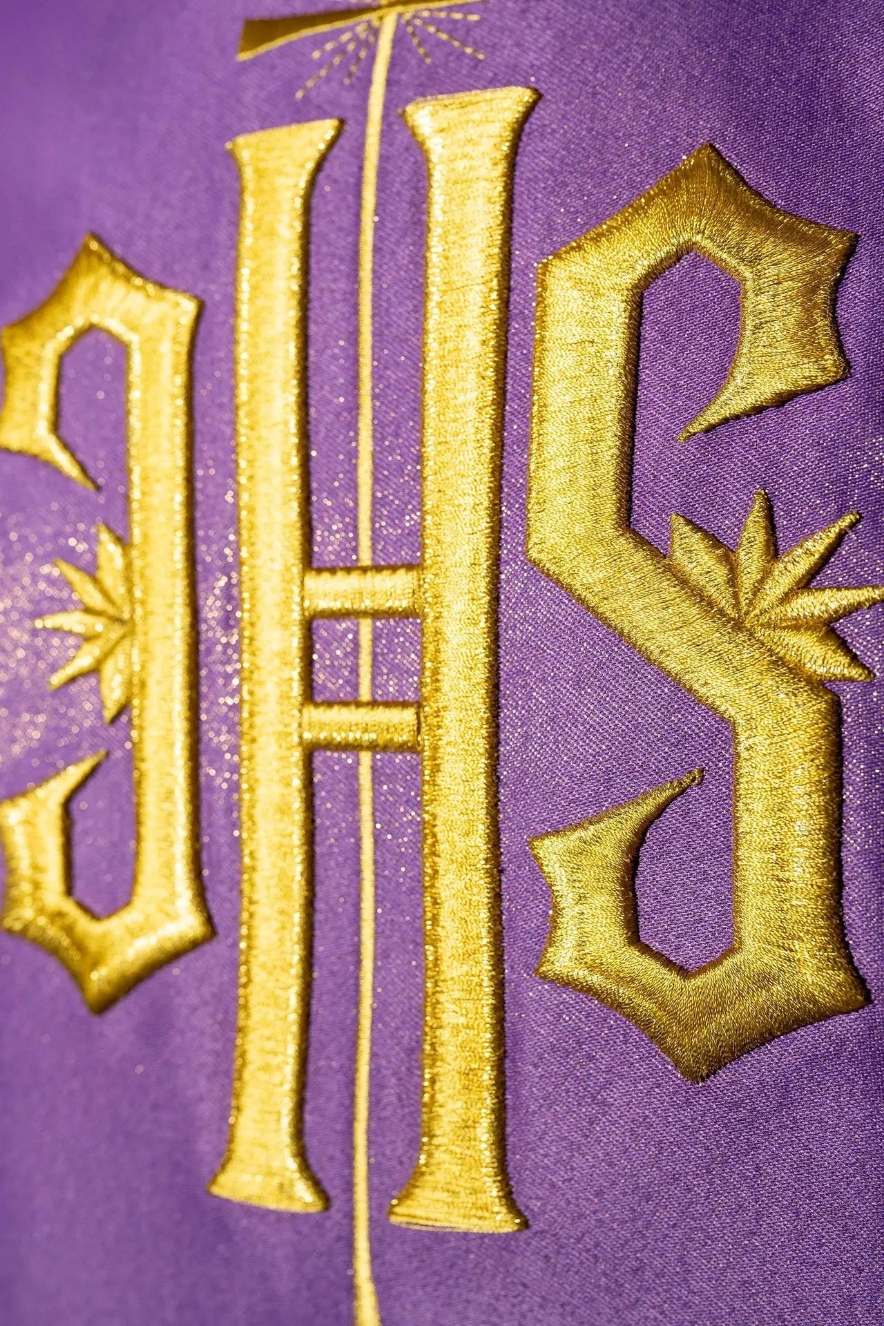 Richly decorated purple chasuble with a gold motif and a wide IHS sash
