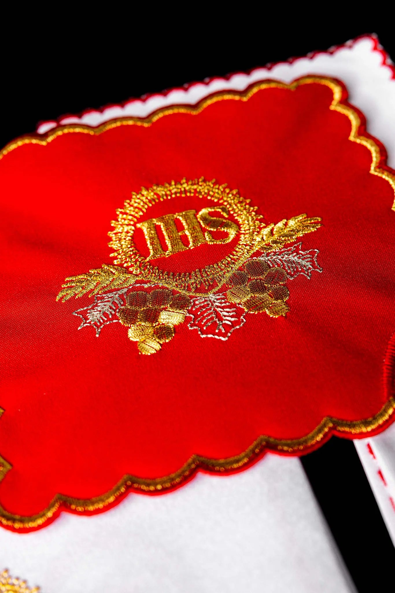 Red chalice linen set with gold IHS embroidery, including a red pall, white corporal, white purificator, and white lavabo towel, all with matching gold IHS symbols and scalloped embroidered edges.