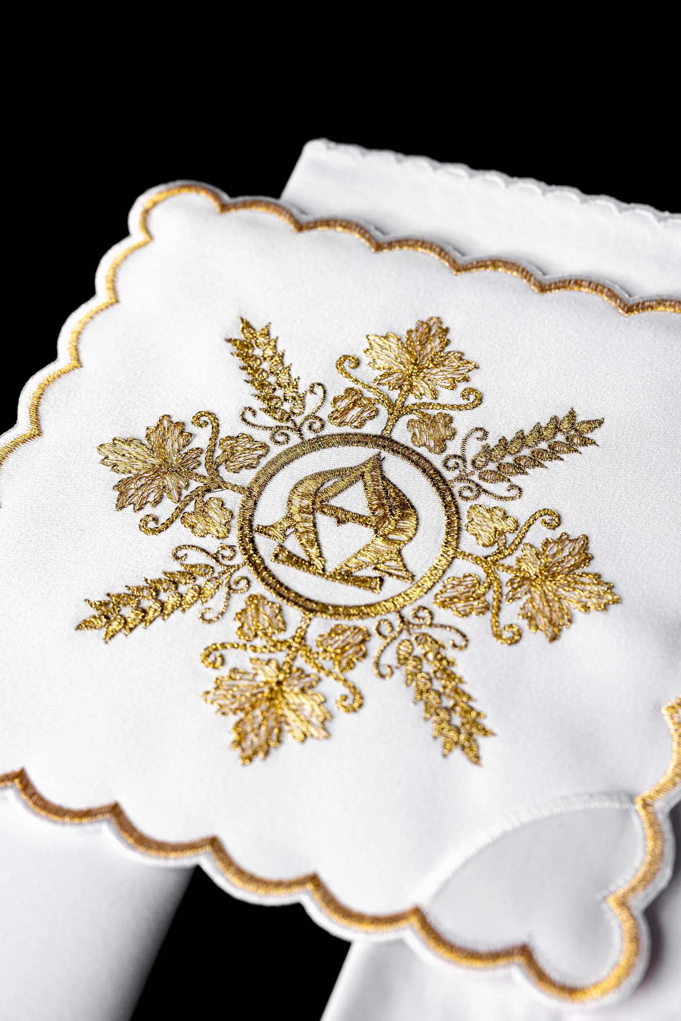 White chalice linen set with gold Alpha and Omega embroidery, including pall, corporal, purificator, and lavabo towel.