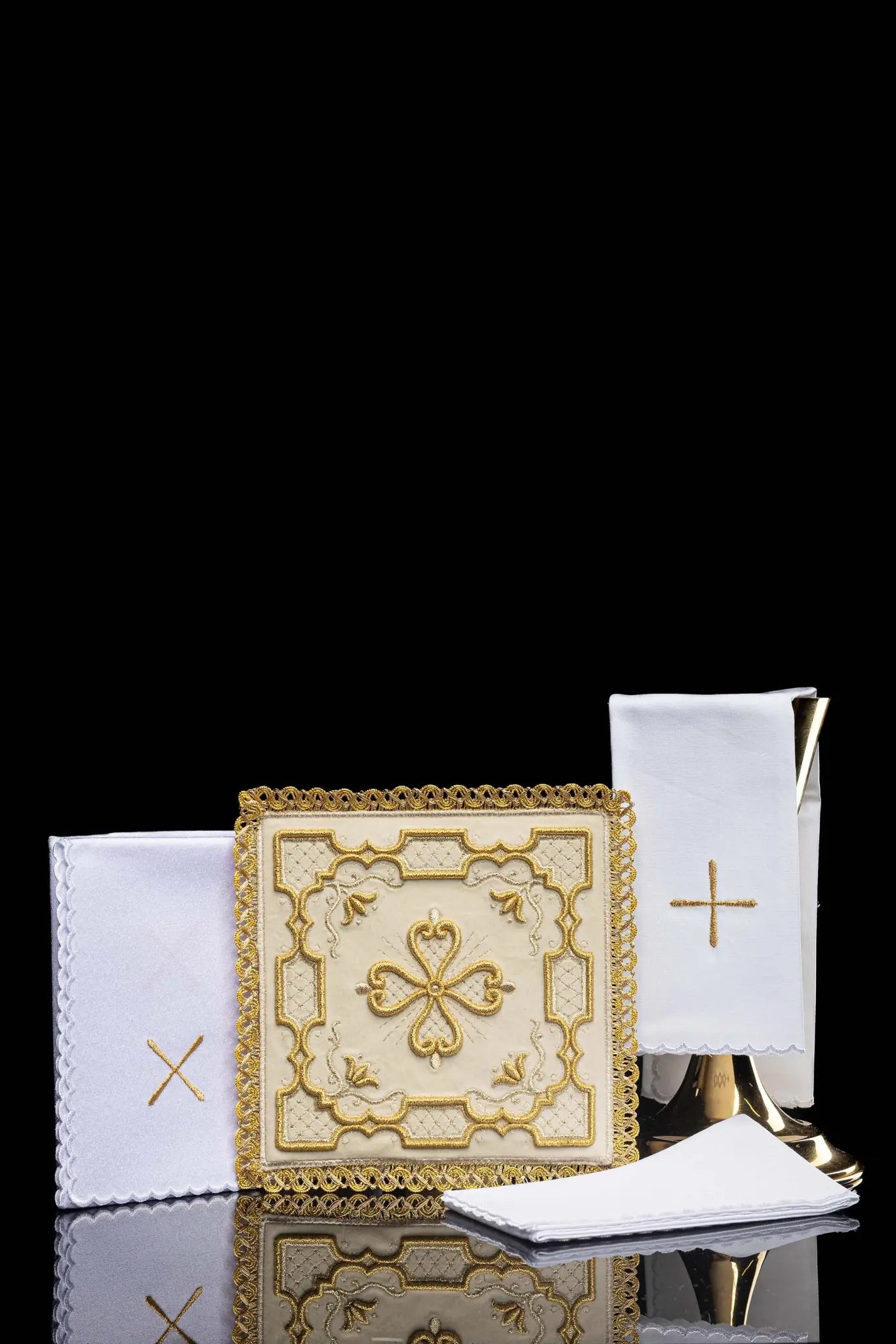 Ecru chalice linen set with velvet pall, corporal, purificator, and lavabo towel. The velvet pall features a central gold embroidered rosette cross with floral and geometric patterns and gold lace trim. The purificator and lavabo towel have a small gold embroidered cross and scalloped edges.