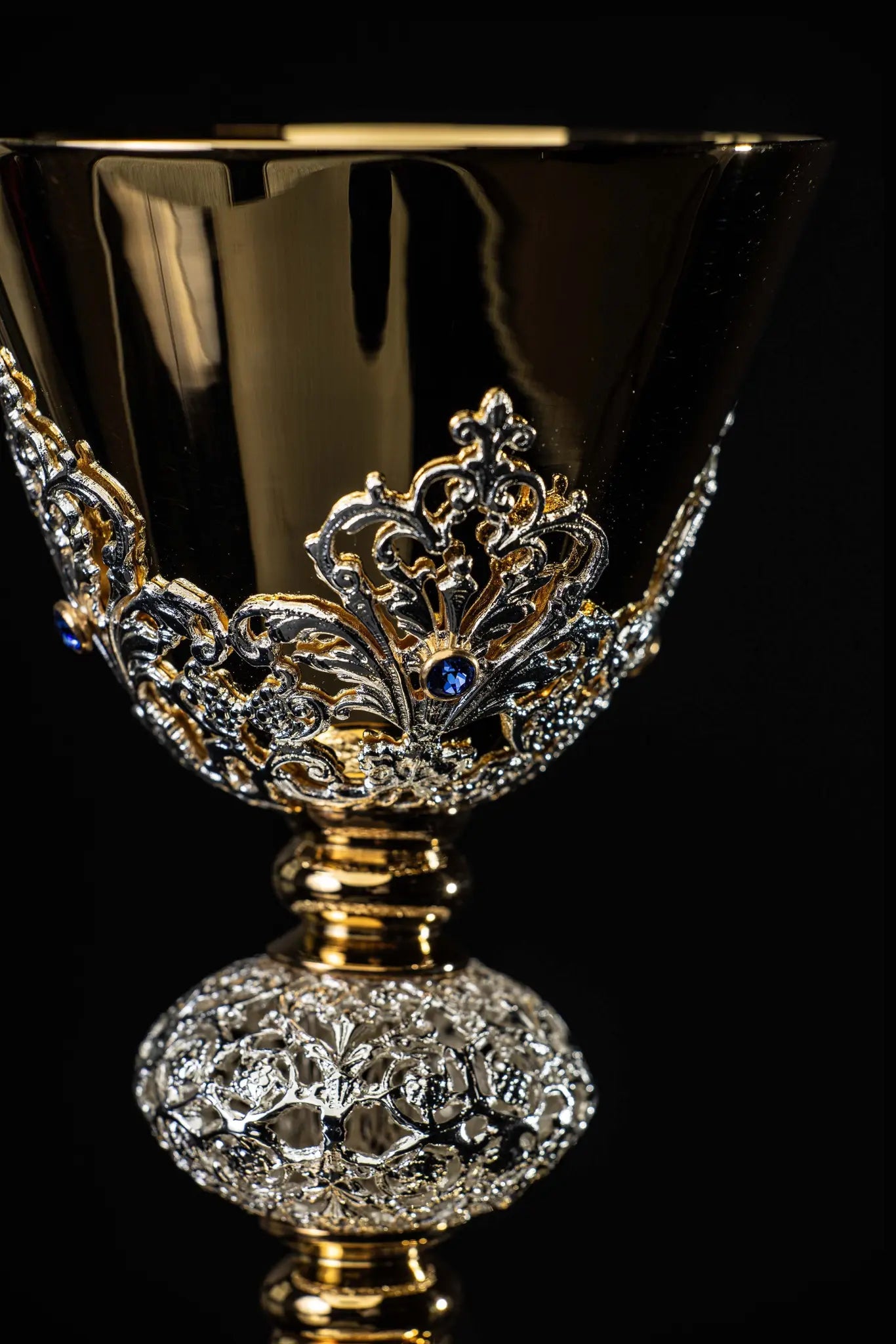 Handmade gold-plated liturgical chalice with silver-plated floral ornamentation and blue sapphire-like stones. The chalice features a decorated cup, nodus, and base.