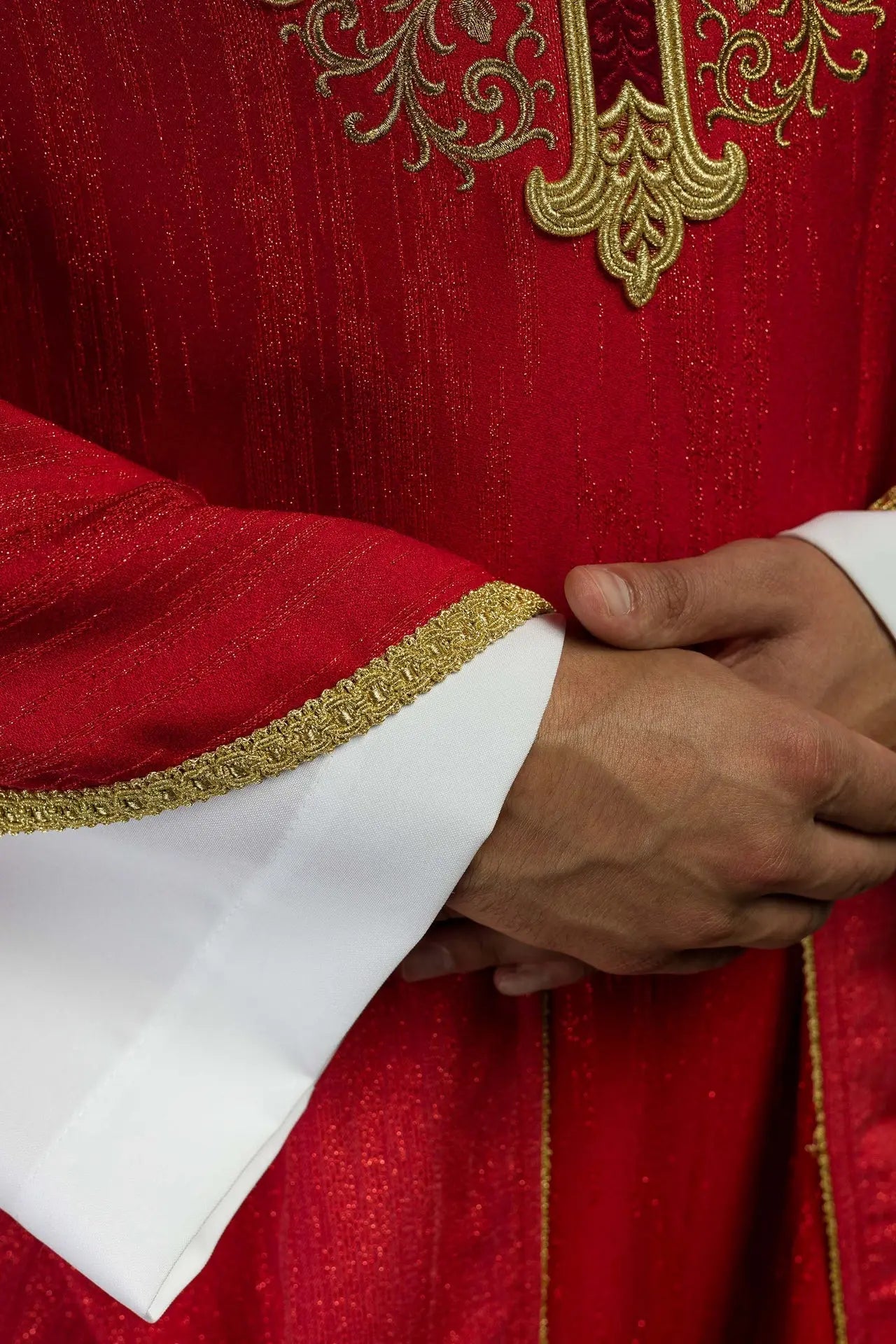 Czerwony ornat z haftowanym motywem krzyża na dekoracyjnej tkaninie 
