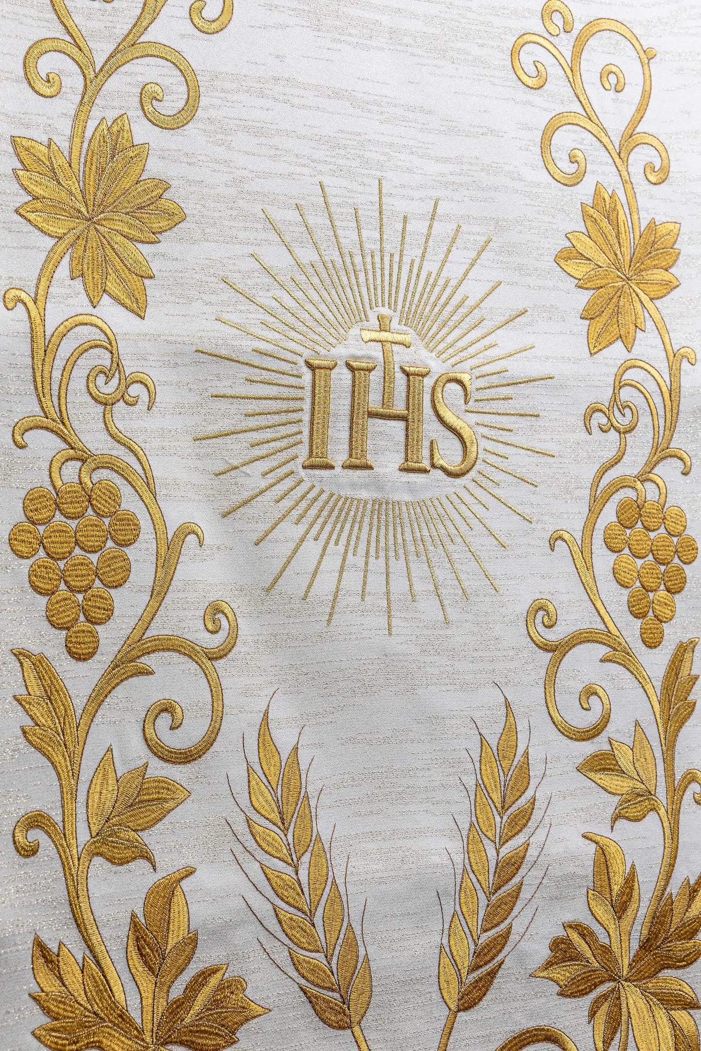 Ecru lectern cover with rich gold IHS monogram embroidery, radiant glory, wheat sheaves, and grapevines, finished with gold fringes.