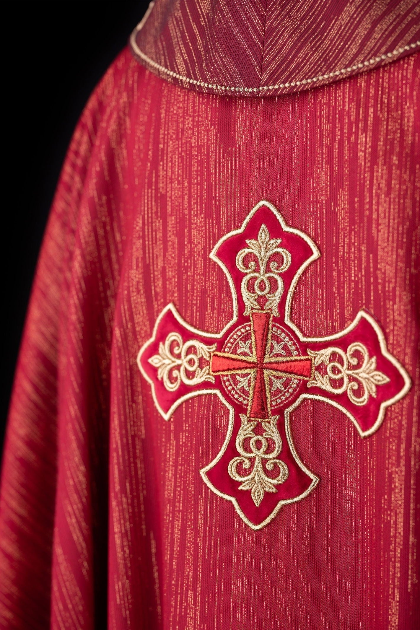 Czerwony ornat liturgiczny z bogato haftowanym krzyżem i zdobionym kołnierzem