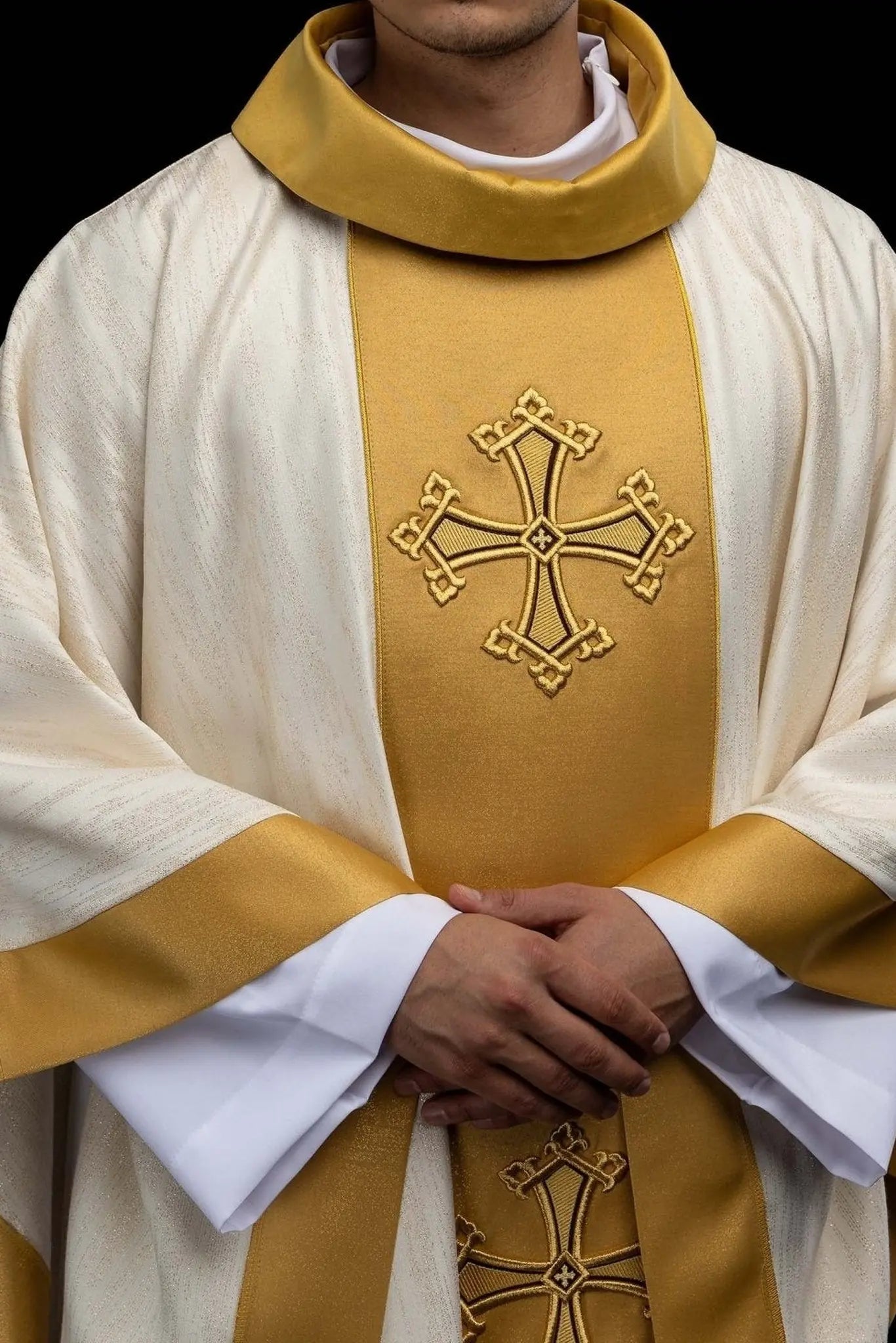 Ecru chasuble with embroidered cross motif and gold band on decorative fabric