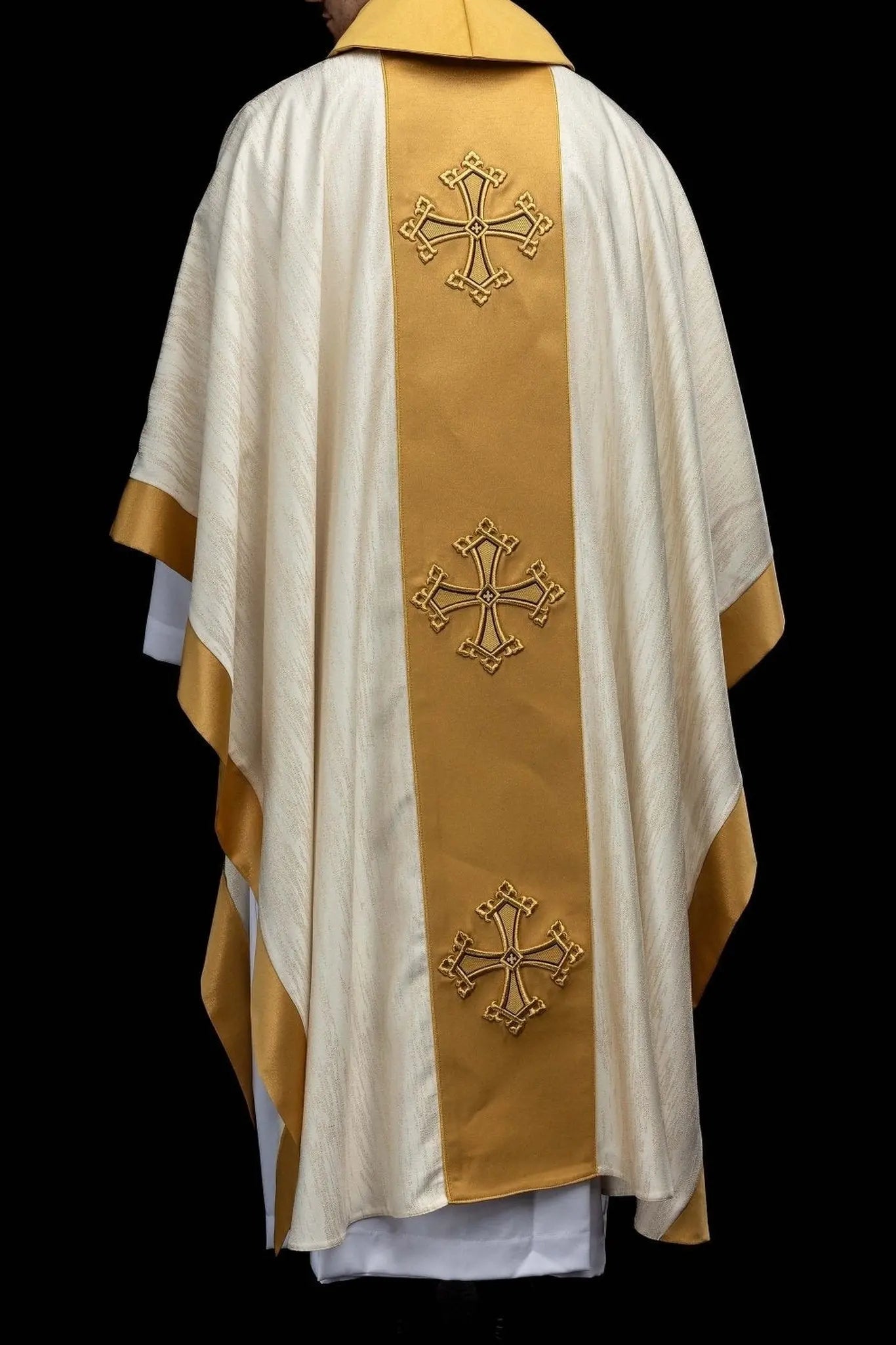 Ecru chasuble with embroidered cross motif and gold band on decorative fabric