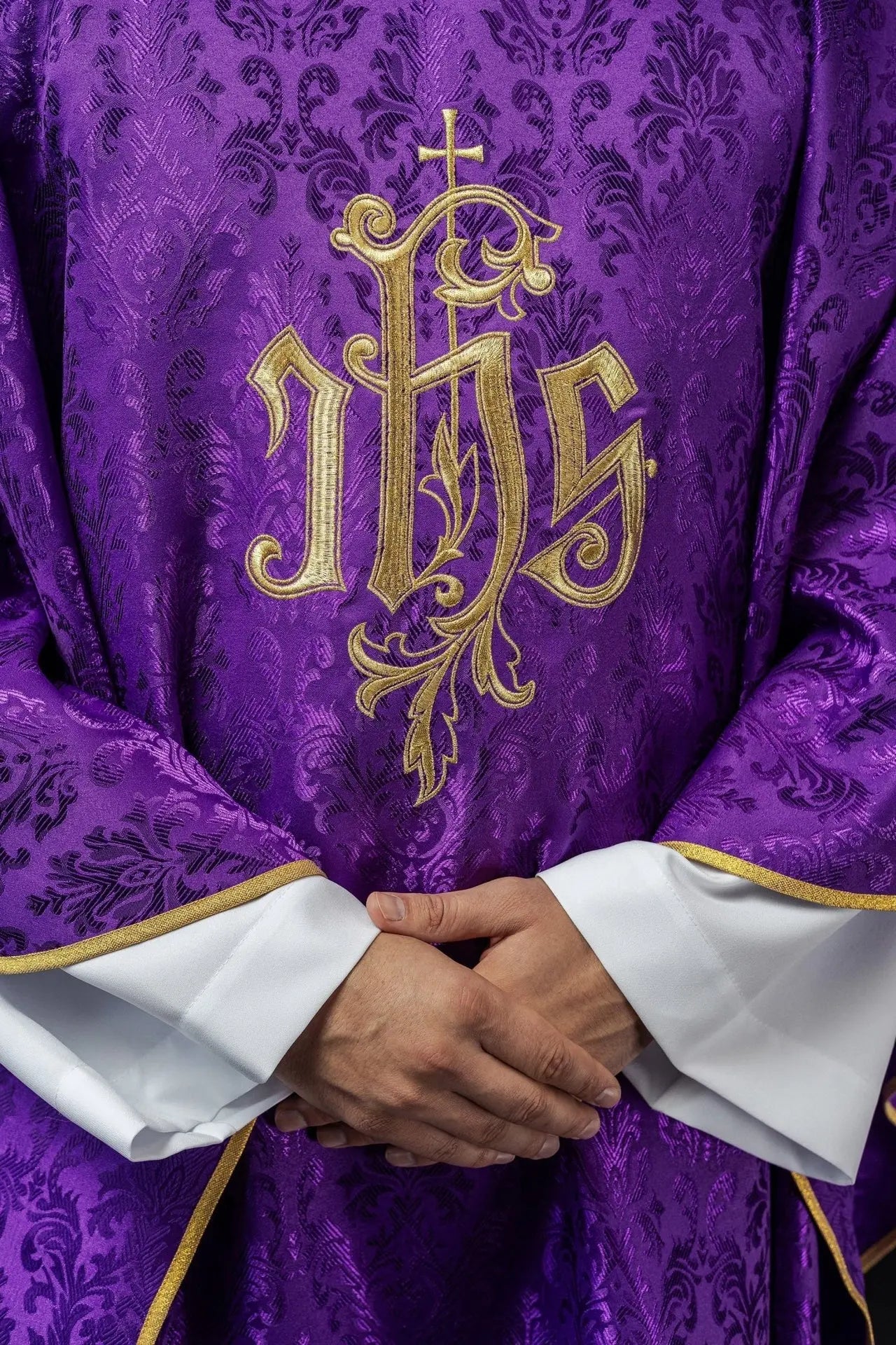 Fioletowy ornat liturgiczny z haftowanym motywem IHS na ozdobnej tkaninie