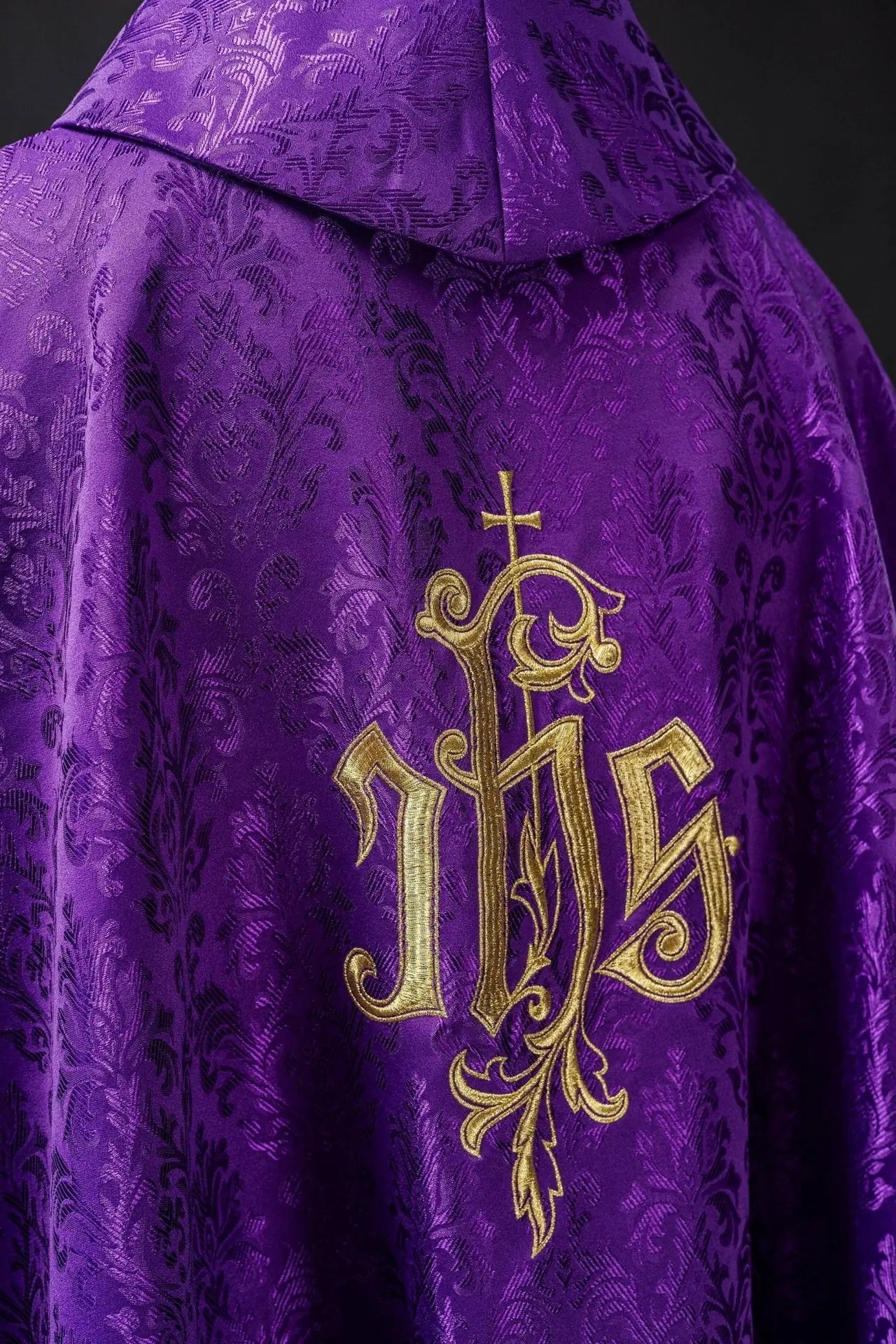 Fioletowy ornat liturgiczny z haftowanym motywem IHS na ozdobnej tkaninie