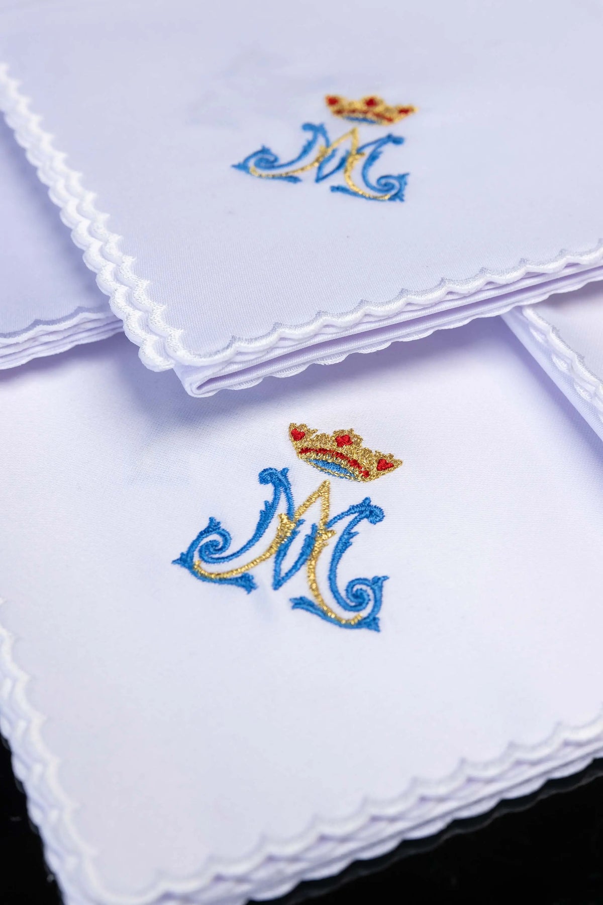 Białe korporały liturgiczne z haftem monogramu „M” i korony, zbliżenie na haft i wykończenie