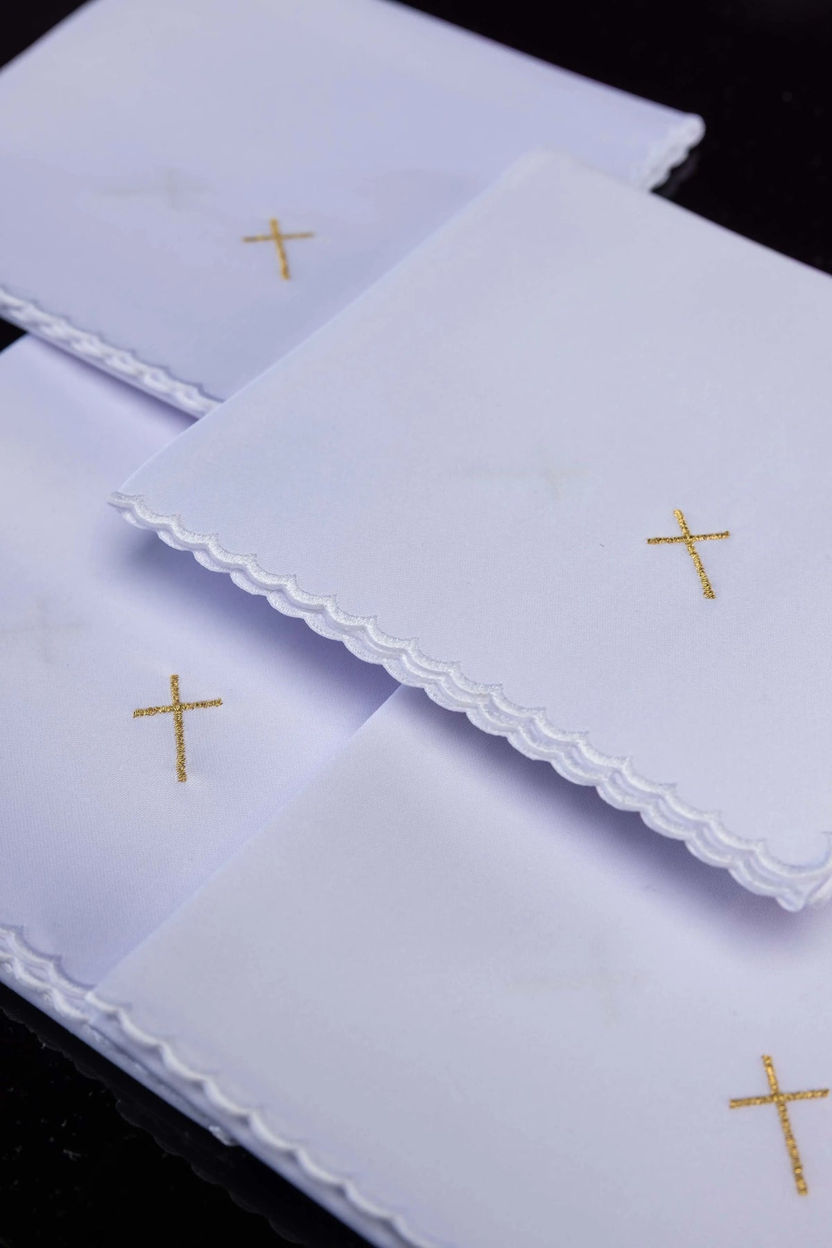 Białe korporały ze złotymi krzyżami i falowanym wykończeniem, zbliżenie