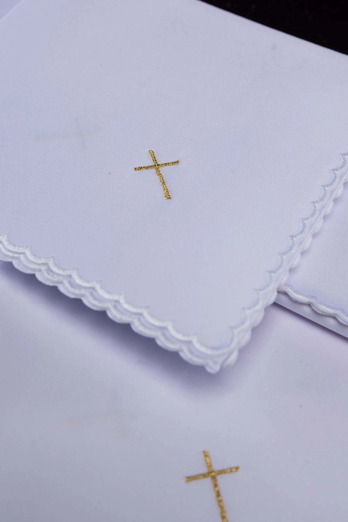 Biały korporał ze złotym haftem krzyża i falowanym brzegiem, zbliżenie