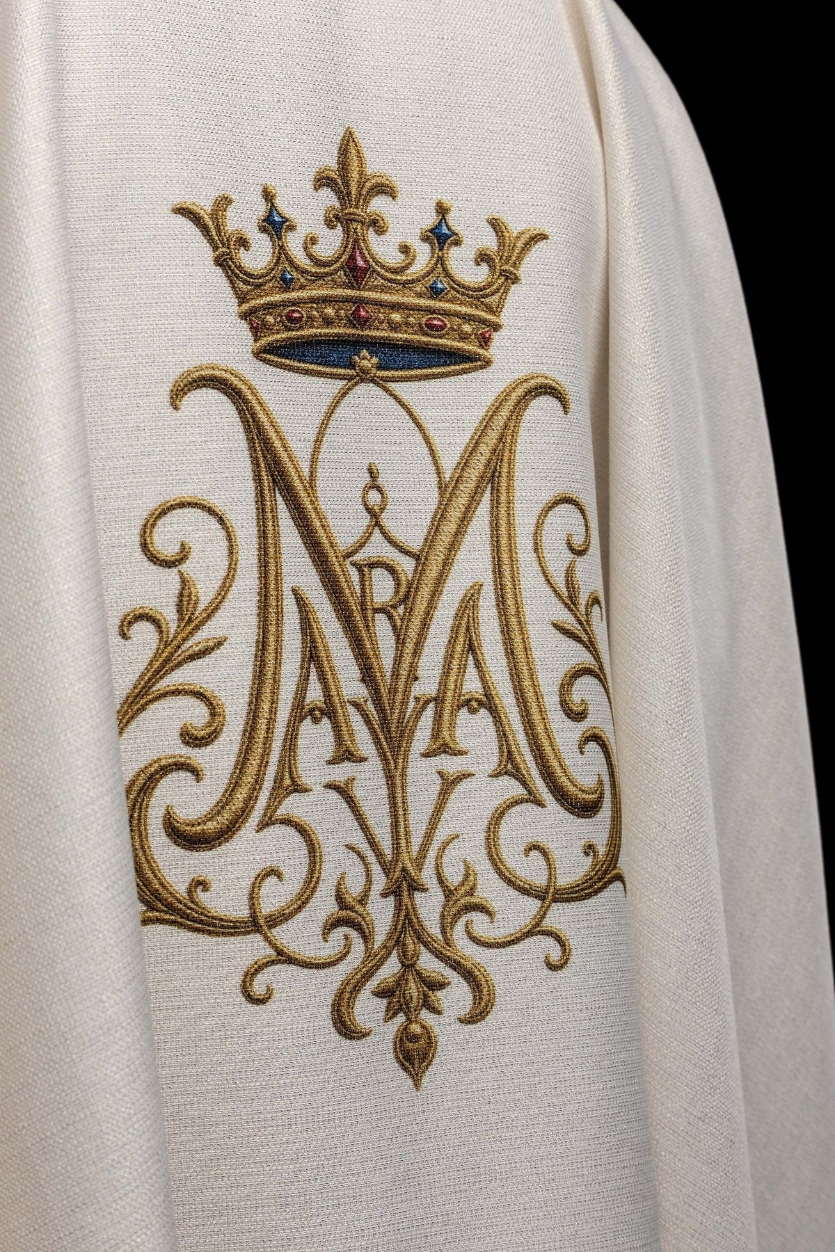Biały ornat z haftowanym monogramem maryjnym pod koroną, zbliżenie haftu z tyłu