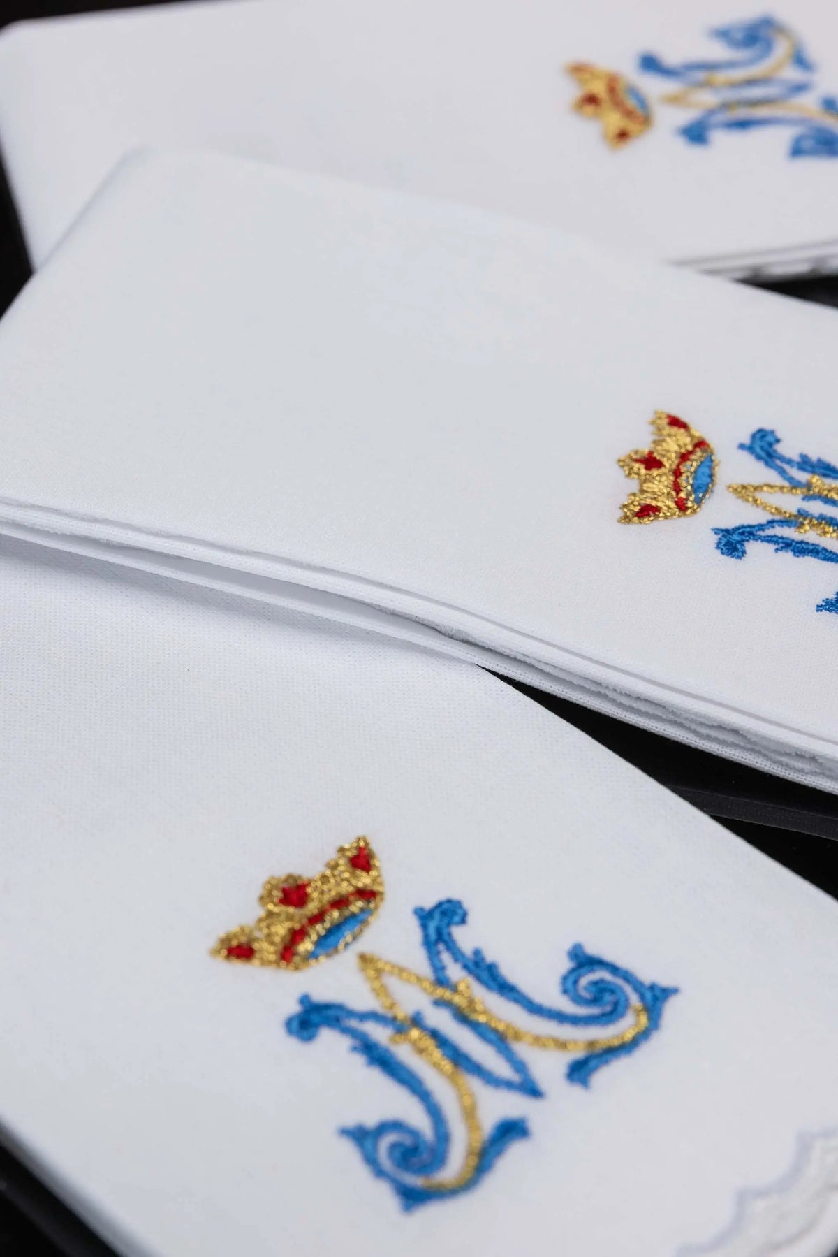 Białe puryfikaterze liturgiczne z haftem monogramu „M” i koroną, zbliżenie
