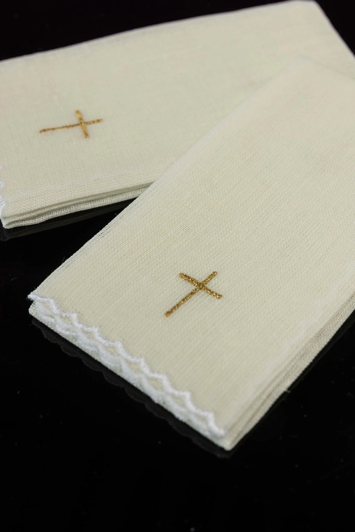 Ecru puryfikaterze liturgiczne ze złotym haftem krzyża i koronkowym brzegiem, zbliżenie