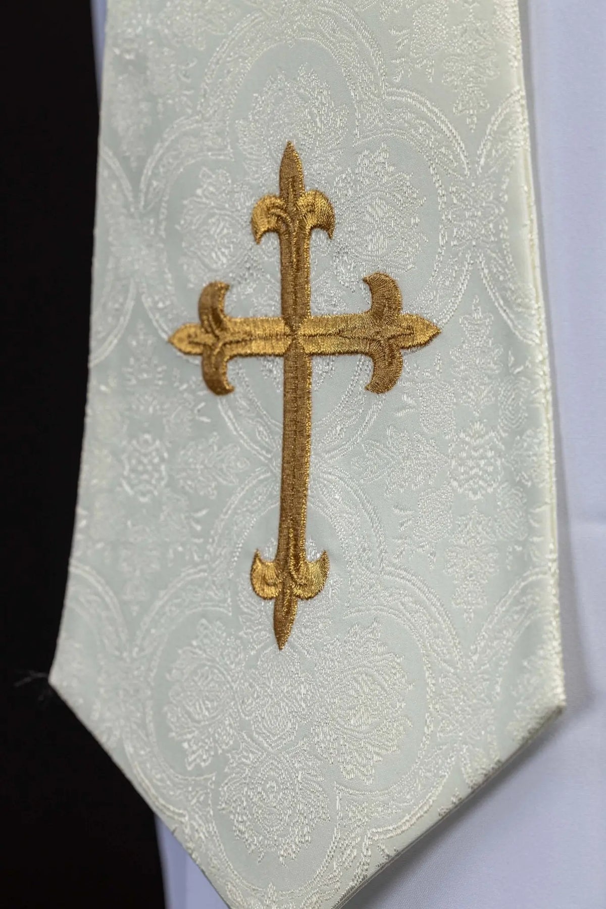 Biała stuła z haftowanym złotym krzyżem, zbliżenie końca