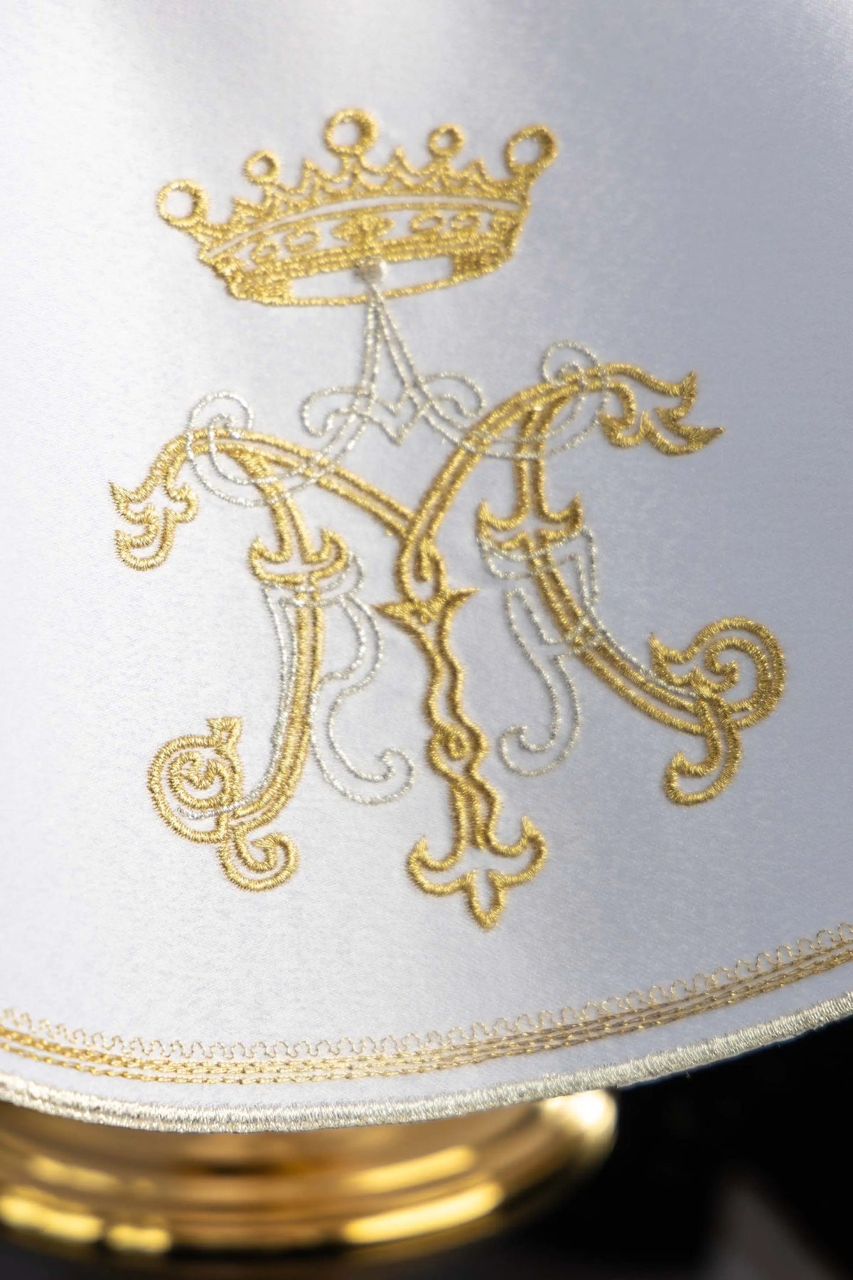 Biały welon na puszkę z monogramem Maryi pod koroną, zbliżenie monogramu i lamówki