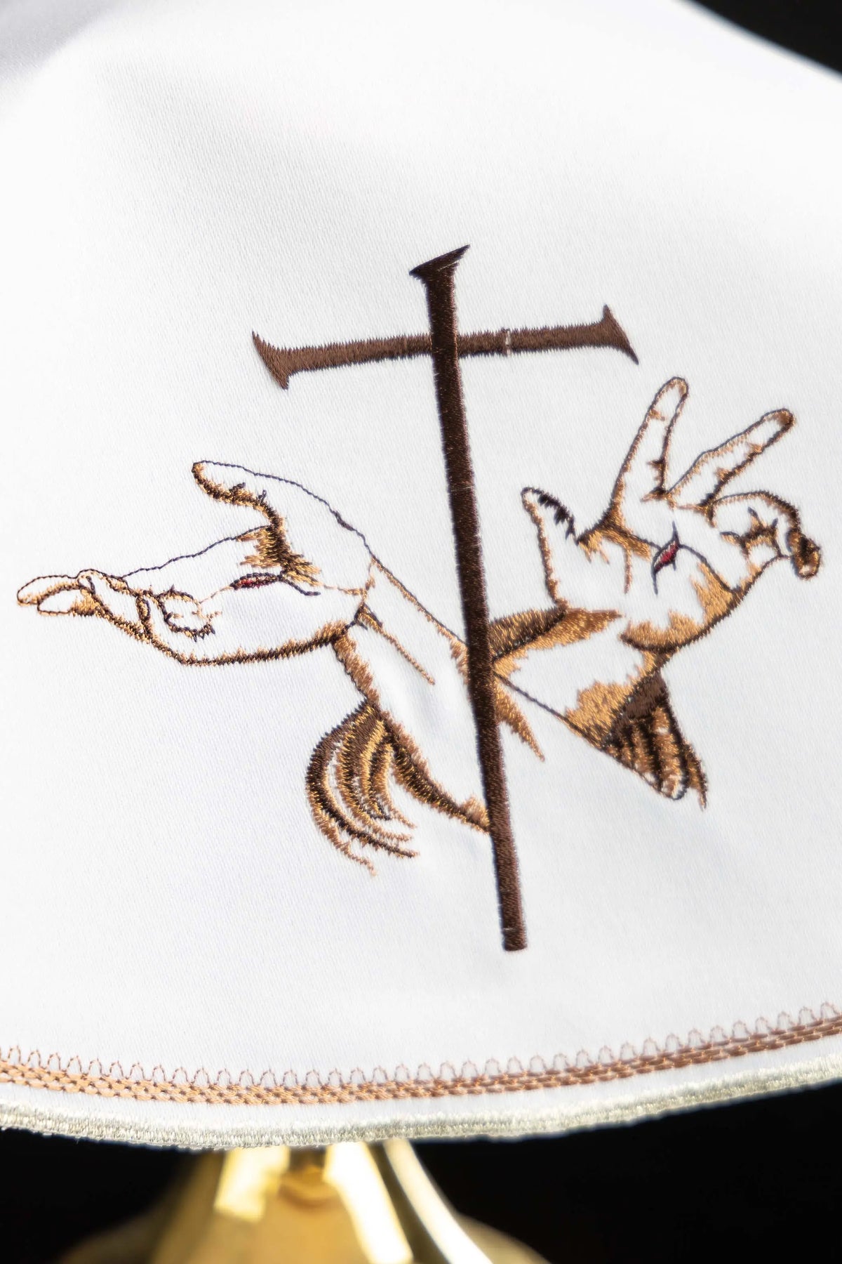 Biały welon franciszkański z krzyżem i skrzyżowanymi rękami, zbliżenie haftu
