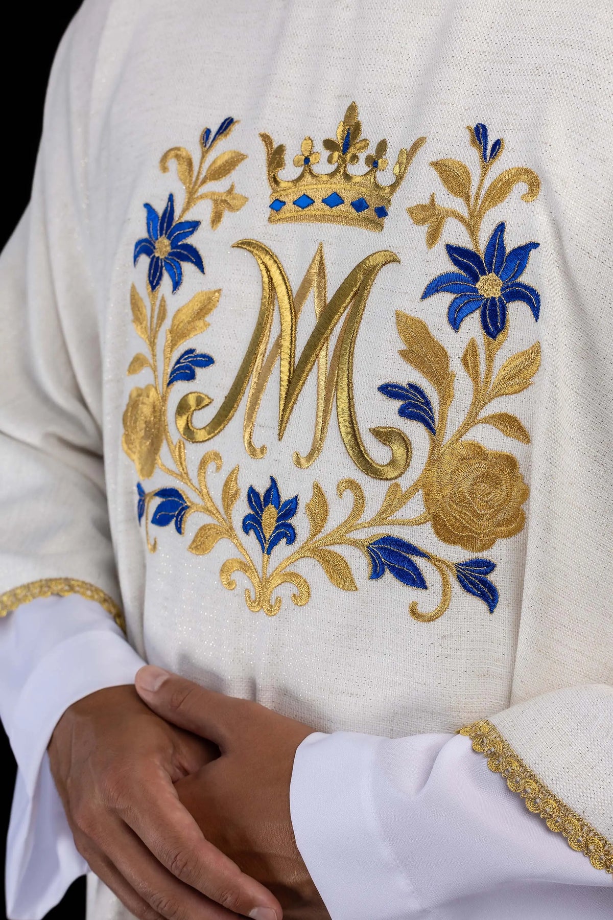 Biała dalmatyka z monogramem „M”, zbliżenie haftu na przodzie
