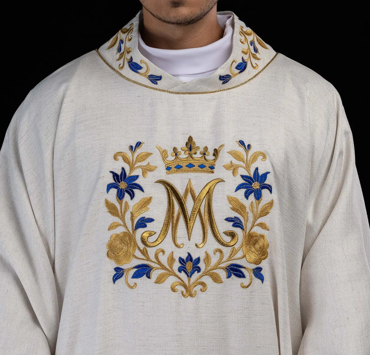 Biała dalmatyka z monogramem „M” i haftowanymi ornamentami, zbliżenie kołnierza