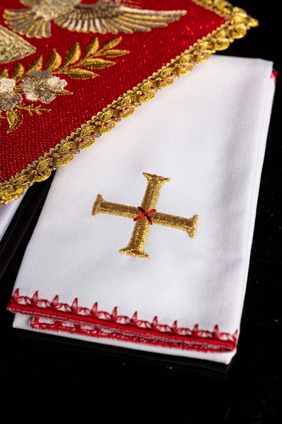 Biała bielizna kielichowa z haftowanym krzyżem i czerwonym wykończeniem, zbliżenie