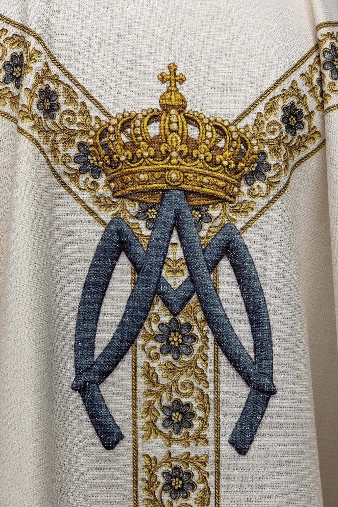 Ecru chasuble with printed image of Our Lady of Lourdes, featuring a blue sash and gold floral motifs, with a matching stole.