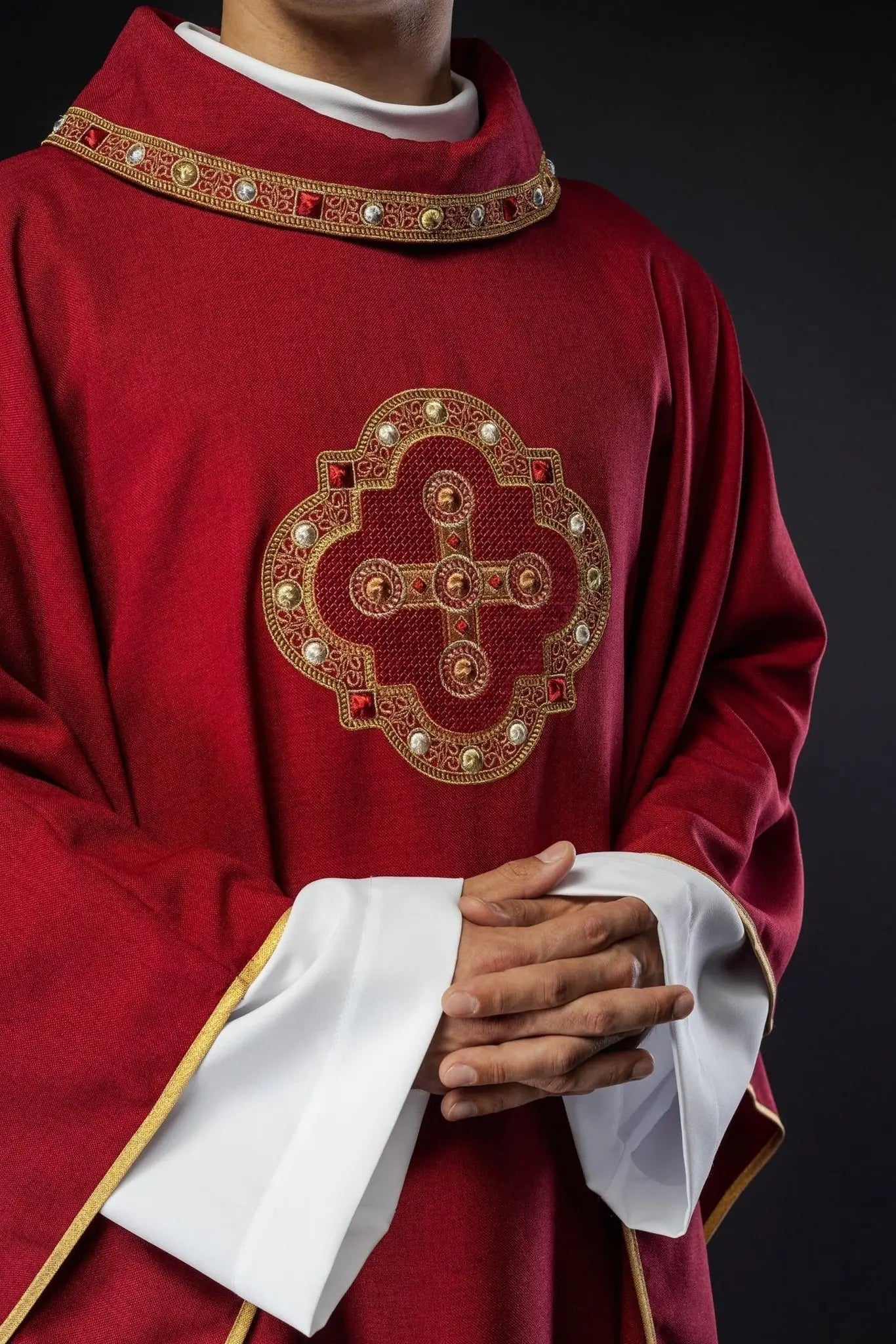 Ornat liturgiczny w czerwonym kolorze z haftowanym wykończeniem na kołnierzu i wokół haftu krzyża