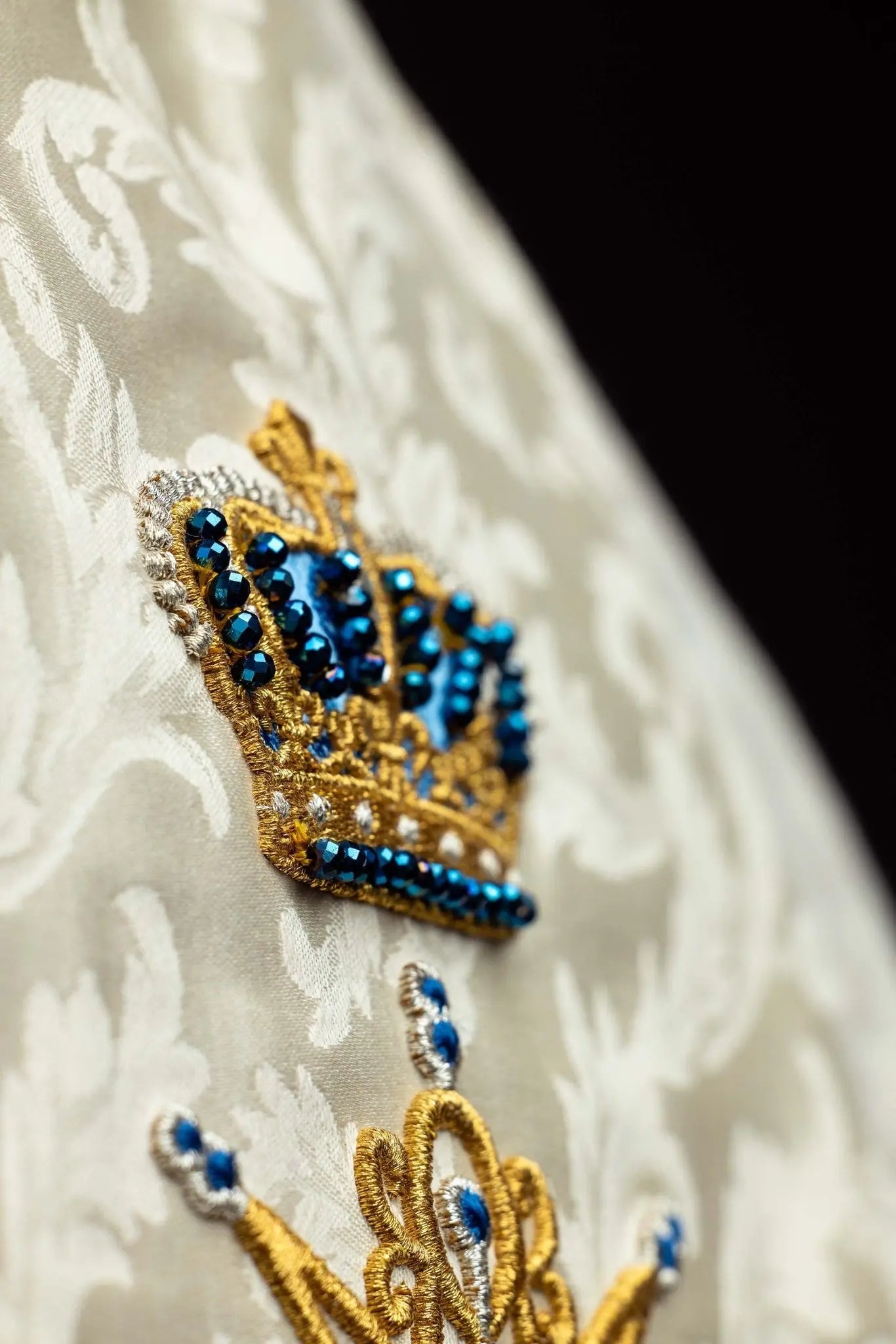 Ecru Marian cope with natural stones and blue velvet trim, part of the Handmade Collection, featuring an ornate metal clasp and gold tassel.
